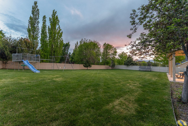 1712 Somerset Ridge Drive Draper, UT 84020 - Photo 74 of 76 Expansive lawn featuring a privacy fence, mature trees, and a covered patio with built-in lighting