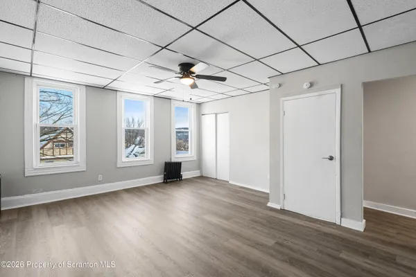a view of an empty room with a window and wooden floor