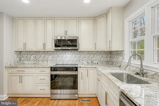 a kitchen with stainless steel appliances granite countertop a stove a sink dishwasher and a microwave oven with wooden cabinets