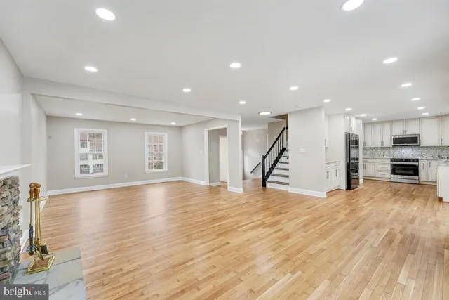 a view of empty room with wooden floor and kitchen
