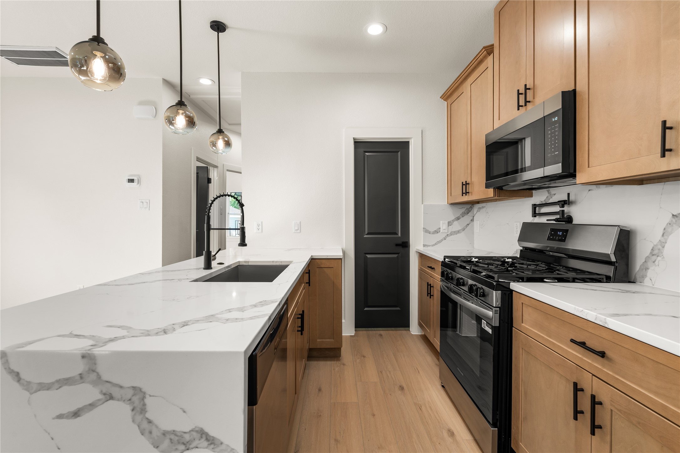 5321 Rue Street Houston, TX 77033 - Photo 9 of 23 Thoughtfully crafted kitchen workspace — sleek gooseneck faucet, pot filler detail, quartz waterfall counter, and adjacent walk-in pantry.