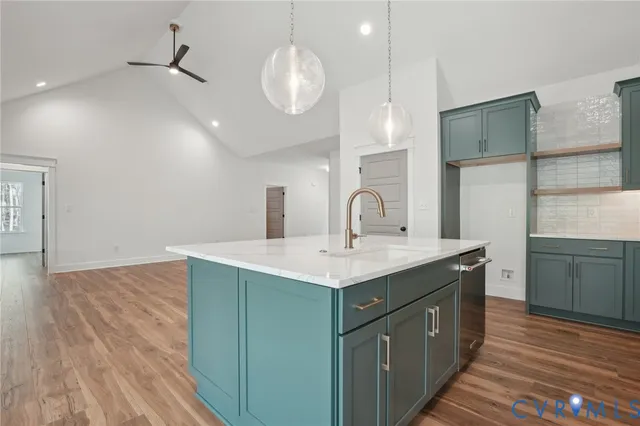 a living room with kitchen island granite countertop wooden floor and a sink
