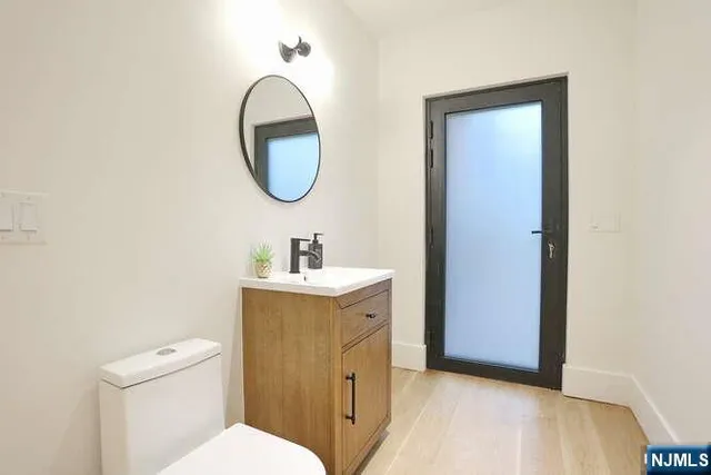 a bathroom with a sink a mirror a toilet and a window
