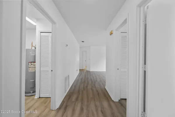 a view of a hallway with wooden floor and a bathroom