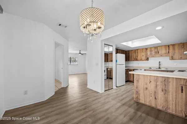 a kitchen with stainless steel appliances granite countertop a refrigerator a sink dishwasher a stove and white cabinets with wooden floor