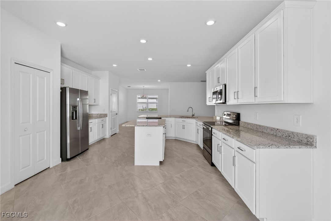 17364 Walnut Run Drive Alva, FL 33920 - Photo 18 of 50 a large kitchen with stainless steel appliances granite countertop a stove a sink a refrigerator and white cabinets with wooden floor