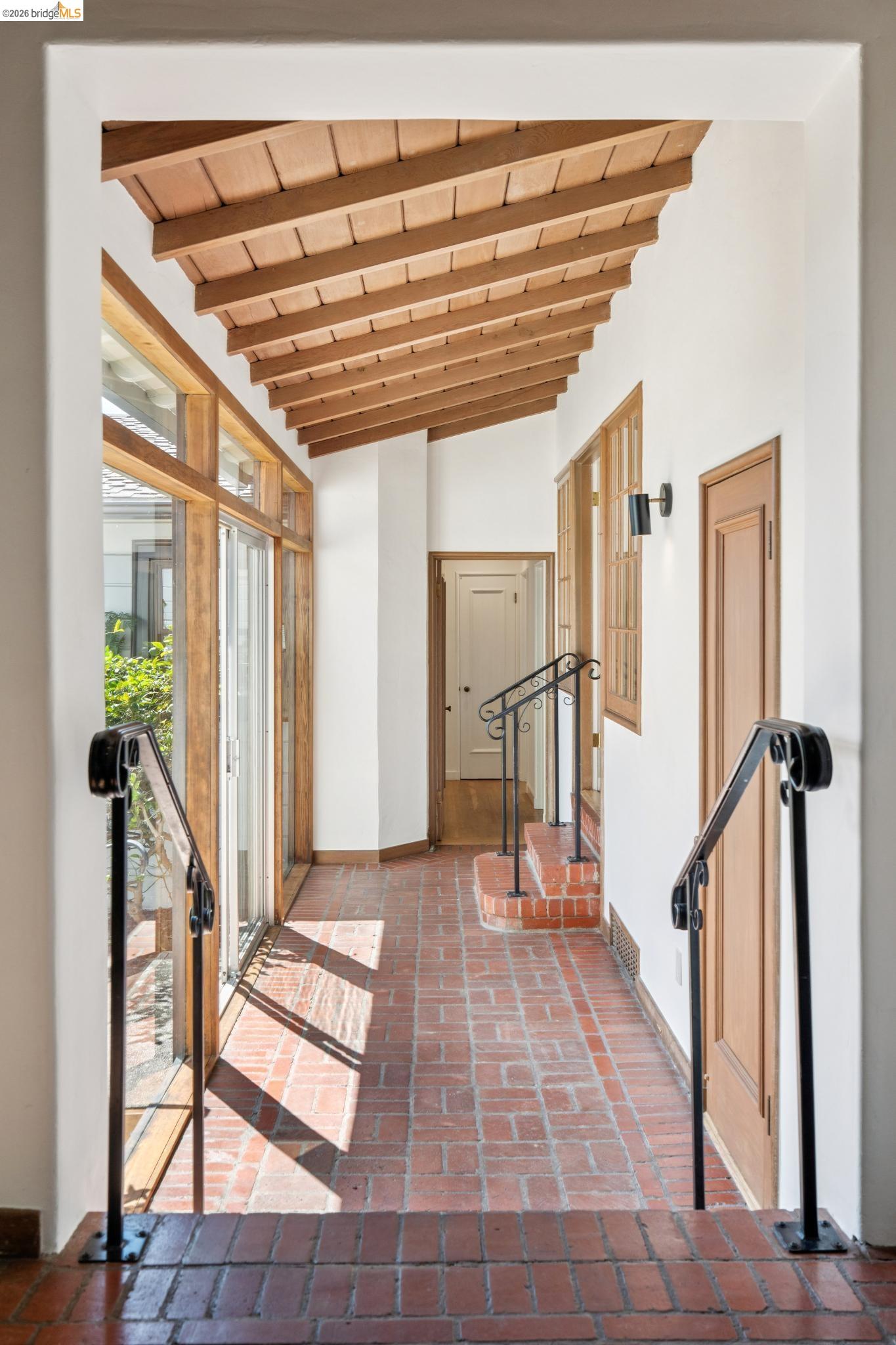 38 Highgate Road Kensington, CA 94707 - Photo 10 of 78 Exposed wood beam ceiling, brick flooring, wrought iron railings, wood-framed windows, and a wood door