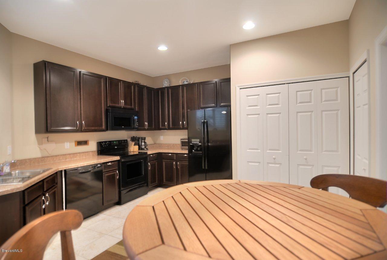 620 Bismarck Way Indialantic, FL 32903 - Photo 6 of 14 a kitchen with stainless steel appliances kitchen island granite countertop a refrigerator a sink dishwasher a stove with wooden cabinets and dining table