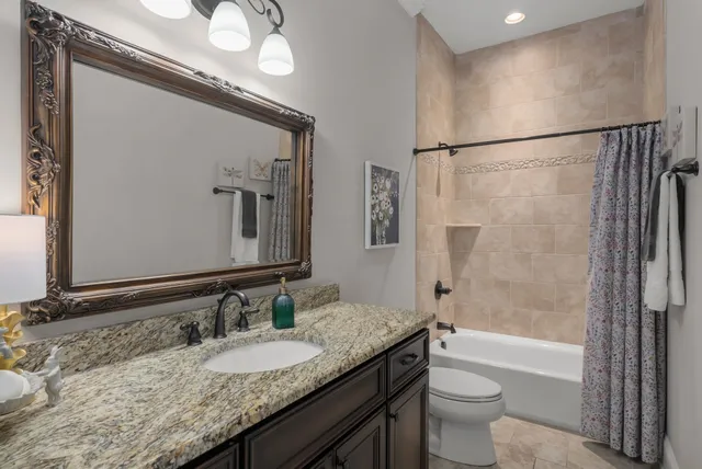 a bathroom with a granite countertop sink mirror toilet and bathtub