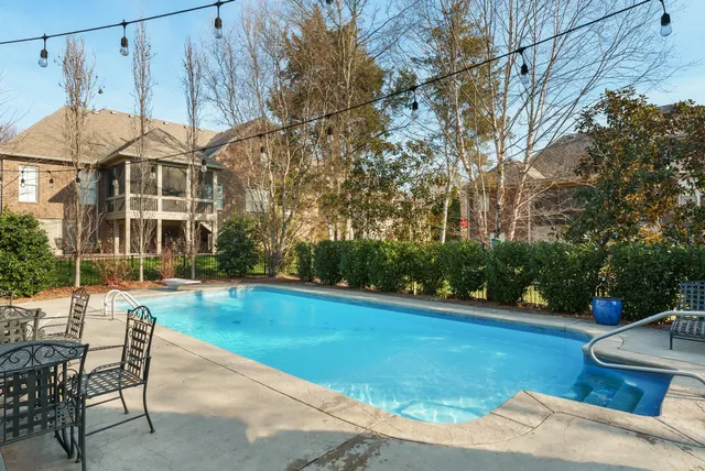 a view of a swimming pool with lawn chairs and plants