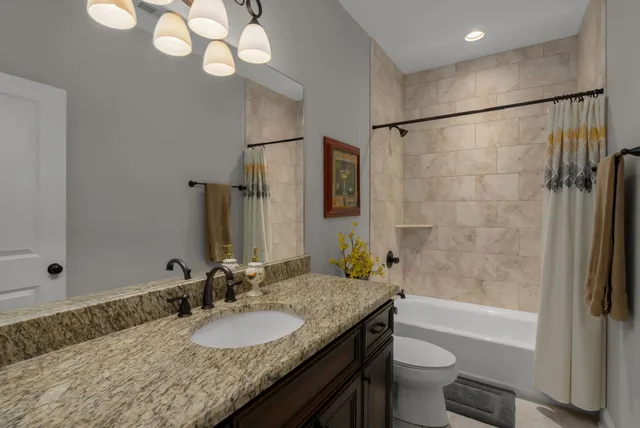 a bathroom with a granite countertop sink a toilet and shower