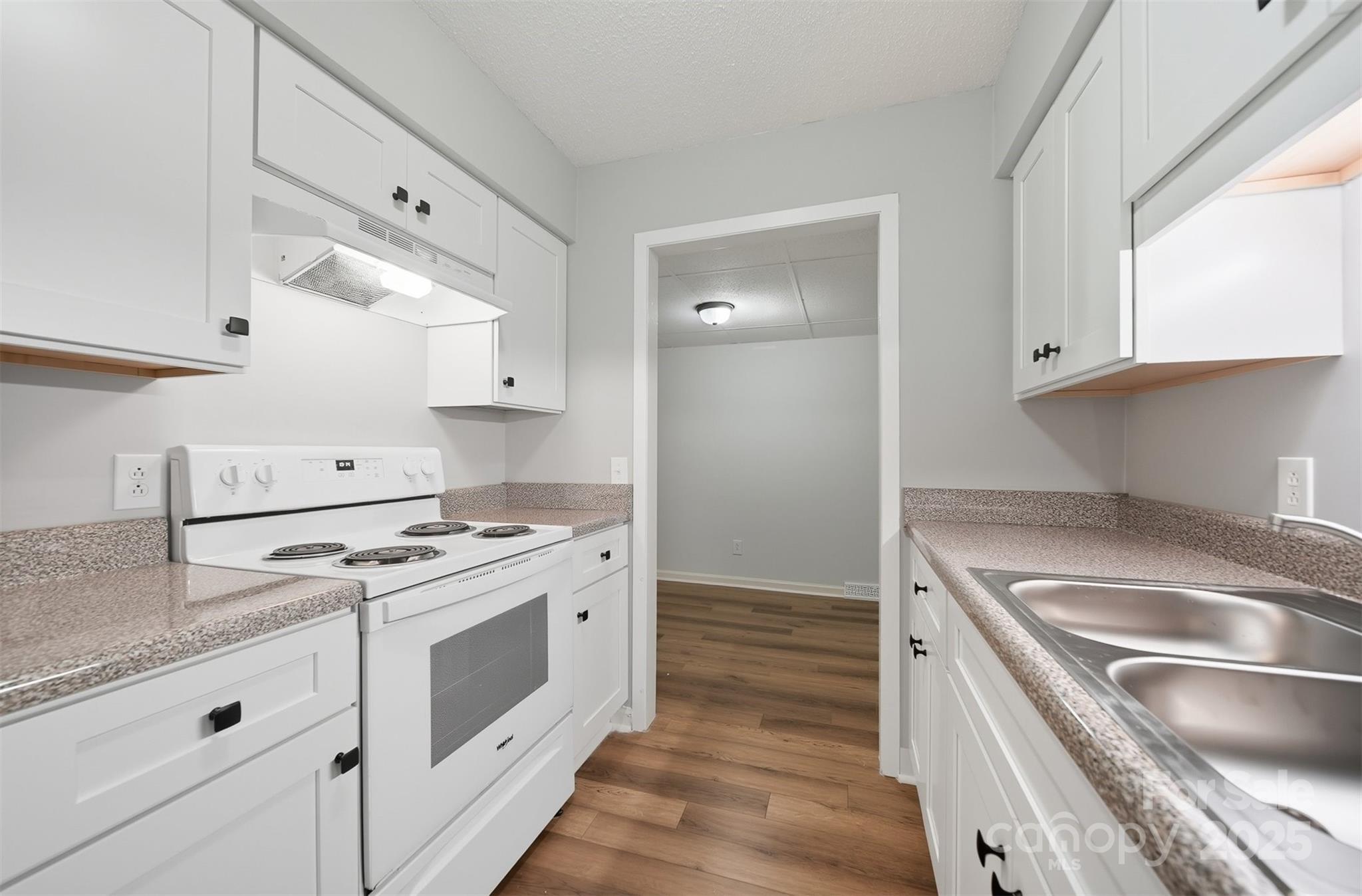824 6th Street Northwest, Unit 5 Hickory, NC 28601 - Photo 7 of 33 a kitchen with granite countertop a sink stainless steel appliances and white cabinets