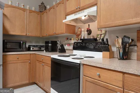 a kitchen with stainless steel appliances granite countertop a sink a stove and white cabinets