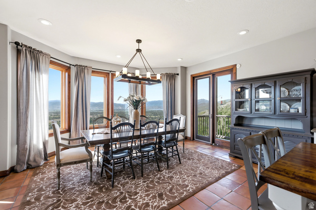335 Bern Way Midway, UT 84049 - Photo 23 of 88 Dining area featuring expansive bay windows with wood trim, terracotta tile flooring, and a contemporary chandelier