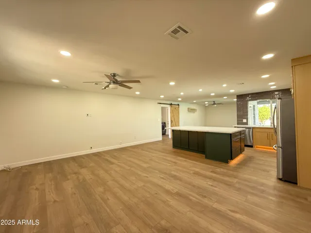 a view of an empty room and a kitchen