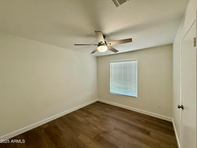 an empty room with wooden floor fan and windows