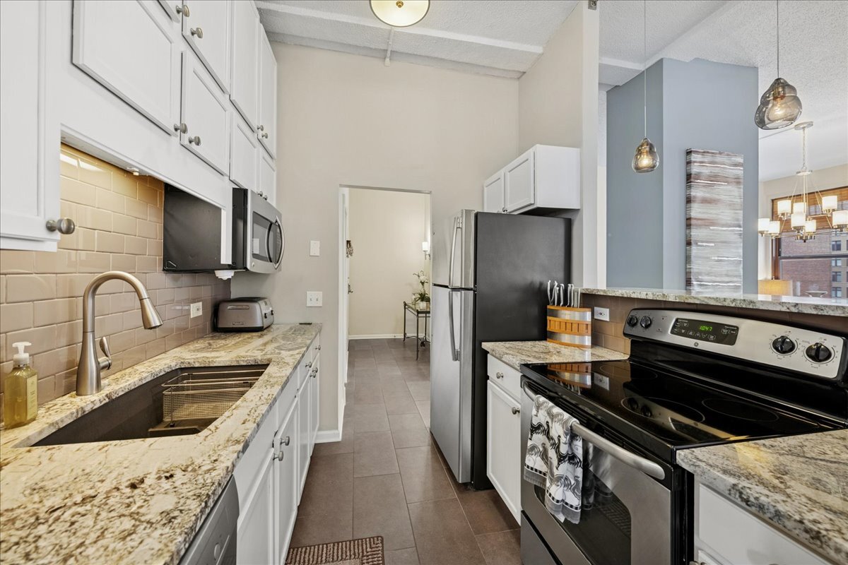 600 South Dearborn Street, Unit 601 Chicago, IL 60605 - Photo 12 of 18 a kitchen with stainless steel appliances granite countertop a stove a sink dishwasher a refrigerator and a stove with wooden floor