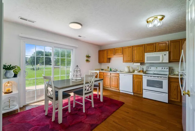 a kitchen with a table chairs refrigerator and window