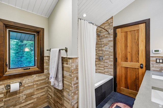 10205 East Moose Loop Road Salt Lake City, UT 84121 - Photo 20 of 50 Bathroom featuring a tub/shower combination with mosaic tile surround, wood-finish door, and a single window with wood trim