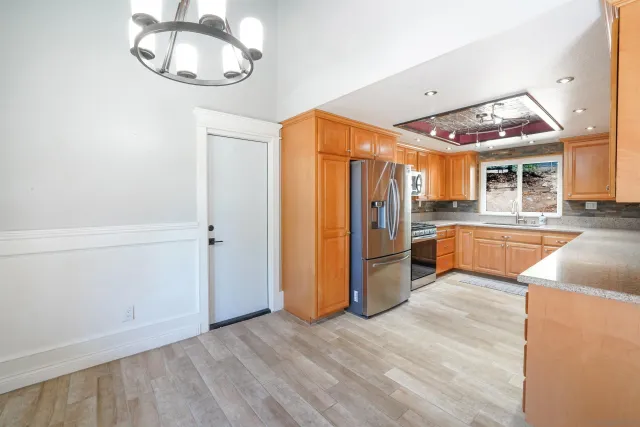 a view of a kitchen with a sink and dishwasher a refrigerator with wooden floor