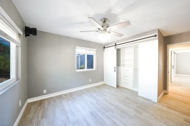 a view of empty room with wooden floor and fan