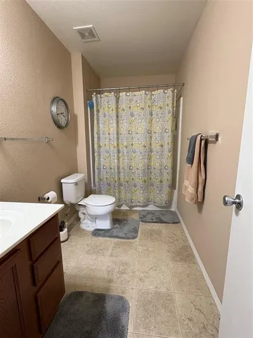 a bathroom with a granite countertop sink a toilet a mirror and shower