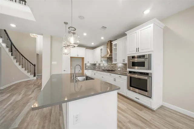 a kitchen with stainless steel appliances granite countertop a sink a stove and a refrigerator
