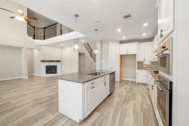 a kitchen with stainless steel appliances kitchen island granite countertop a refrigerator a oven a stove and a sink with wooden floor