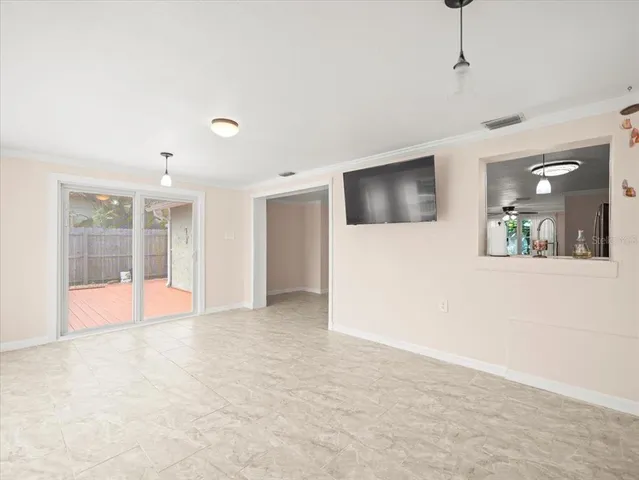 a view of an empty room with a window and a kitchen view
