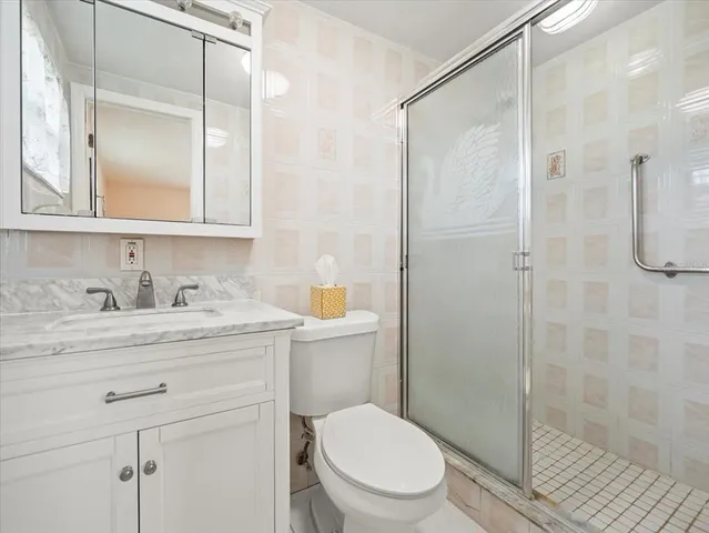 a bathroom with a granite countertop sink toilet a mirror and shower