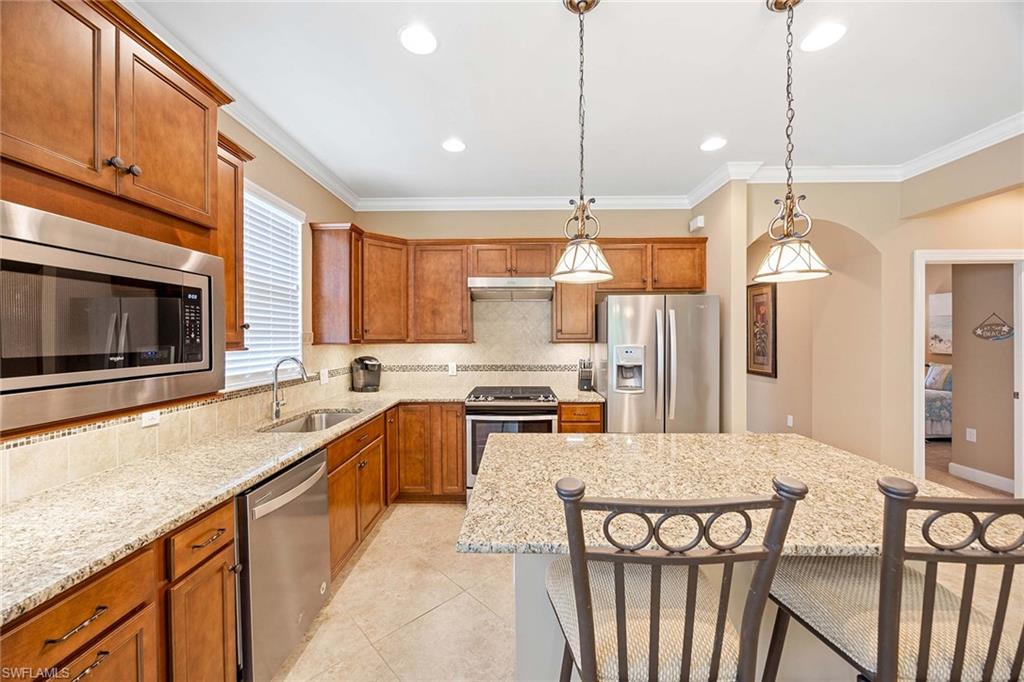 7638 Jacaranda Lane Naples, FL 34114 - Photo 16 of 50 a kitchen with stainless steel appliances granite countertop a stove a sink a microwave a refrigerator and island