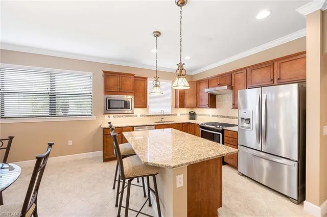 a kitchen with stainless steel appliances granite countertop a refrigerator a stove a sink a dining table and chairs with wooden floor