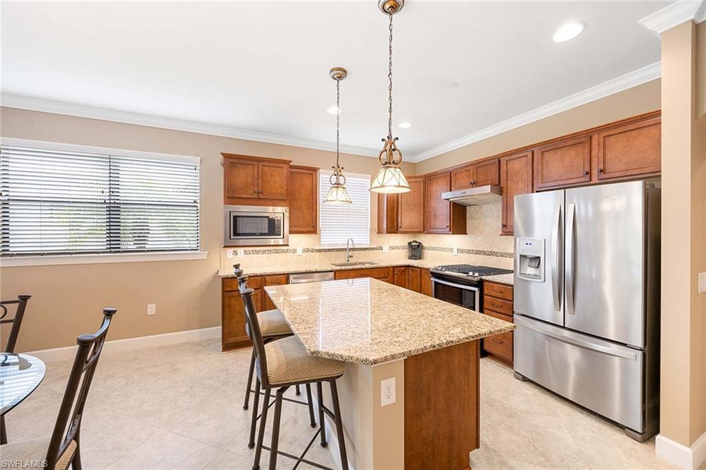 7638 Jacaranda Lane Naples, FL 34114 - Photo 17 of 50 a kitchen with stainless steel appliances granite countertop a refrigerator a stove a sink a dining table and chairs with wooden floor