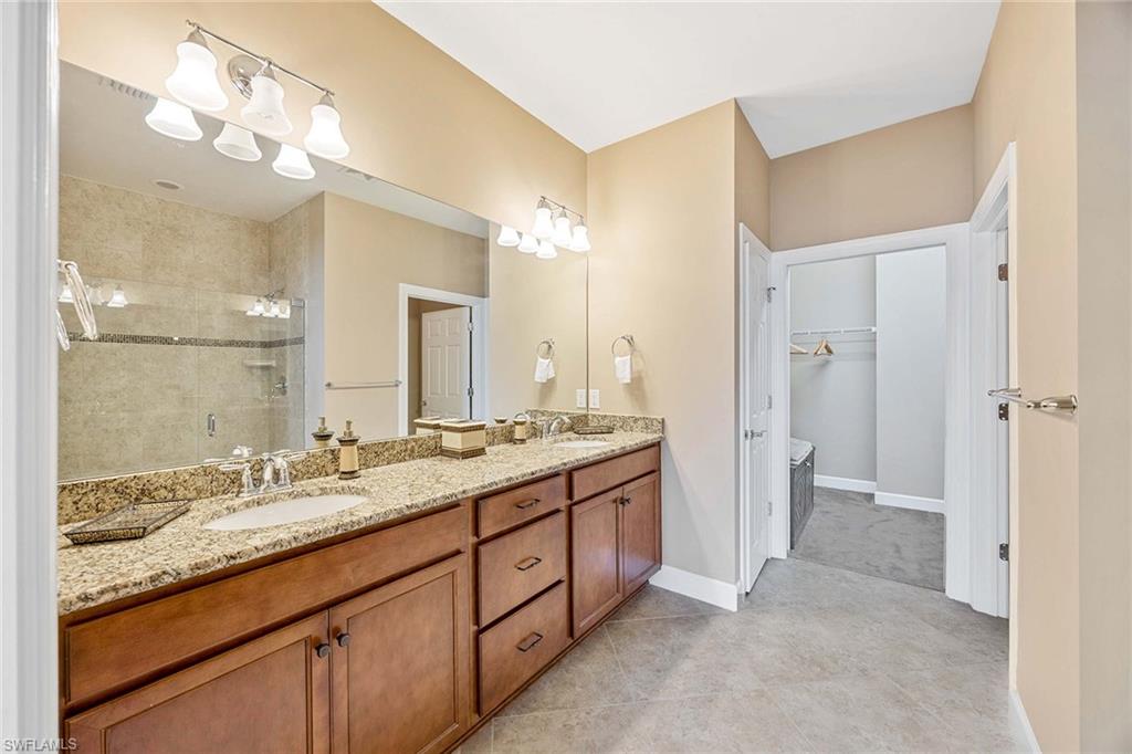 7638 Jacaranda Lane Naples, FL 34114 - Photo 23 of 50 a spacious bathroom with a granite countertop sink mirror and a shower