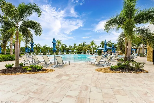 a view of a swimming pool with a lounge chair and palm trees