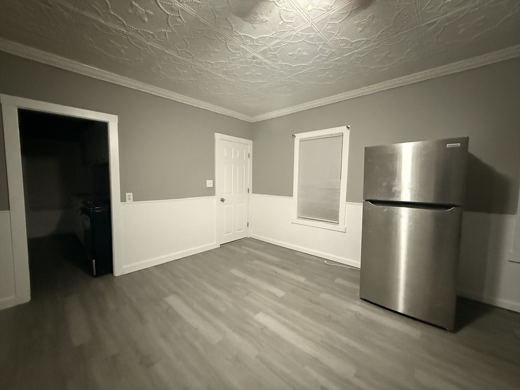 107-113 Palmer Street, Unit 3 Fall River, MA 02724 - Photo 4 of 8 a view of an empty room with wooden floor and a kitchen