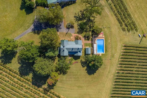 an aerial view of a house with swimming pool and large trees