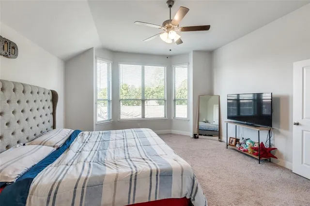 a bedroom with a large bed and a chandelier fan