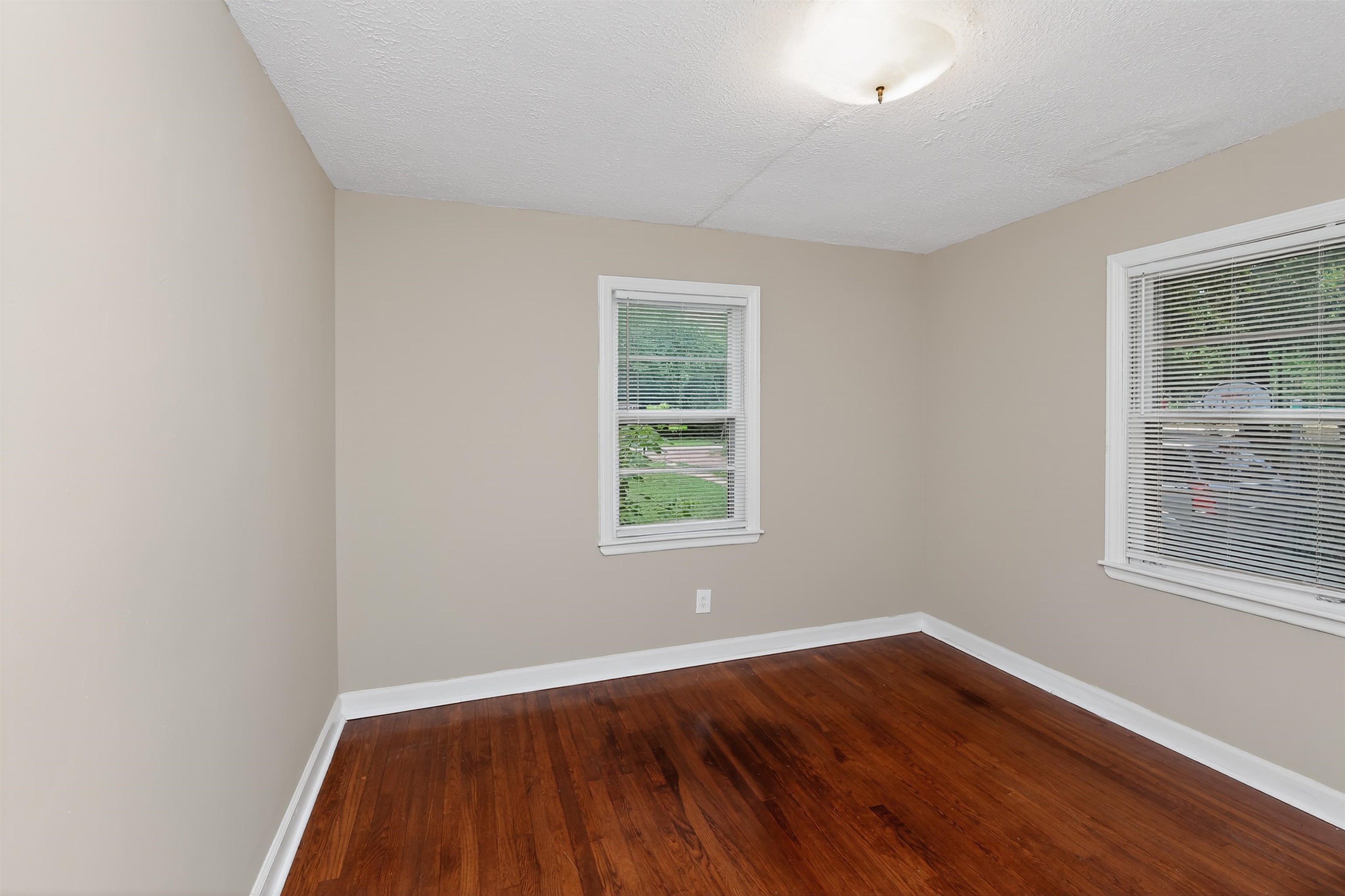 2840 Allen Road Memphis, TN 38128 - Photo 17 of 31 Room featuring rich wood-finish flooring, two windows with blinds, neutral wall paint, white baseboards, and a semi-flush ceiling light fixture