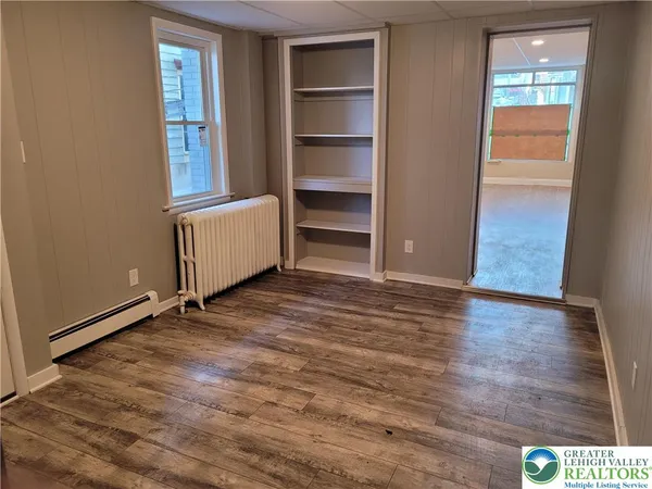 a view of an empty room with a window and wooden floor