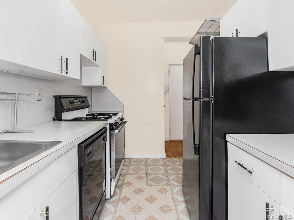 679 West 239th Street, Unit 1C Bronx, NY 10463 - Photo 3 of 13 Kitchen with baseboards, light countertops, black appliances, and white cabinets