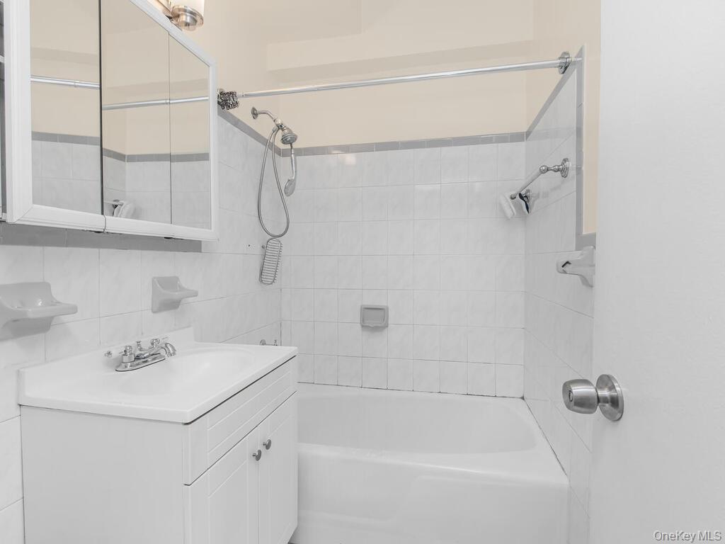 679 West 239th Street, Unit 1C Bronx, NY 10463 - Photo 6 of 13 Bathroom featuring shower combination, tile walls, vanity, and decorative backsplash
