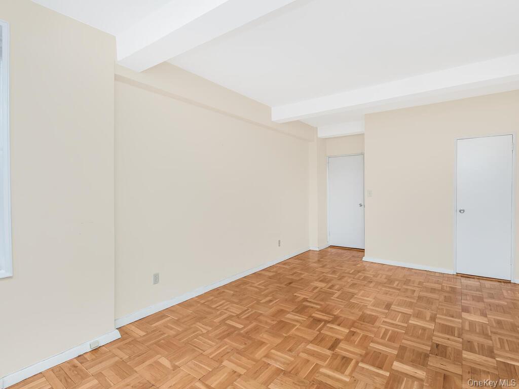 679 West 239th Street, Unit 1C Bronx, NY 10463 - Photo 10 of 13 Unfurnished room featuring beamed ceiling and baseboards