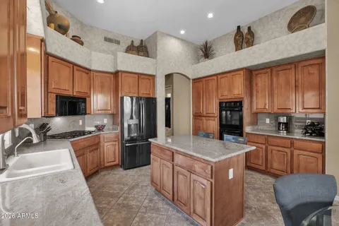 a large kitchen with stainless steel appliances granite countertop a stove refrigerator a sink and dishwasher