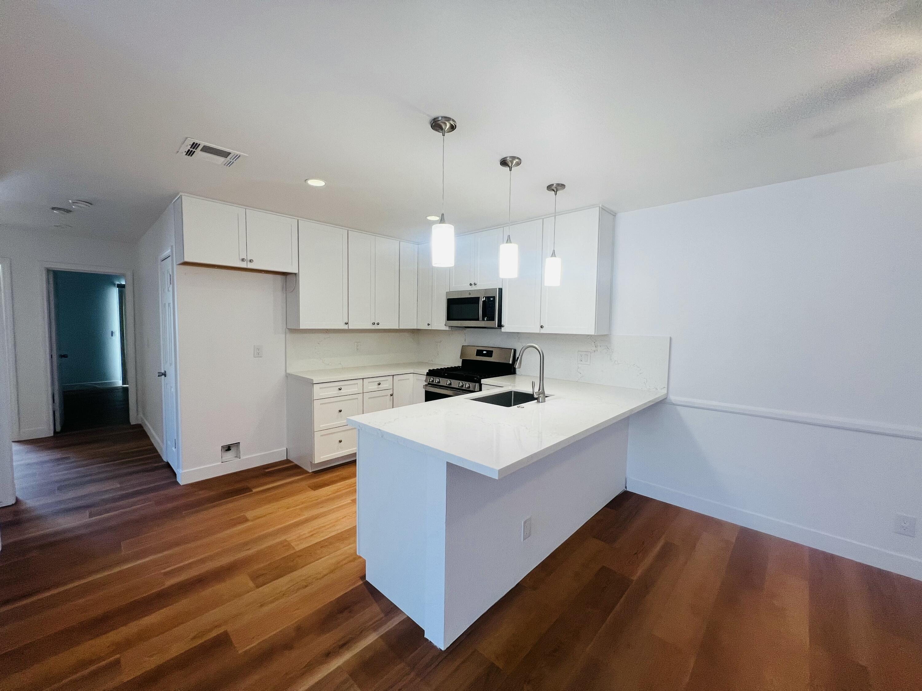 32900 Monte Vista Road Cathedral City, CA 92234 - Photo 4 of 18 a kitchen with wooden floor and white cabinets