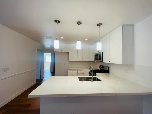a view of a kitchen sink and wooden floor
