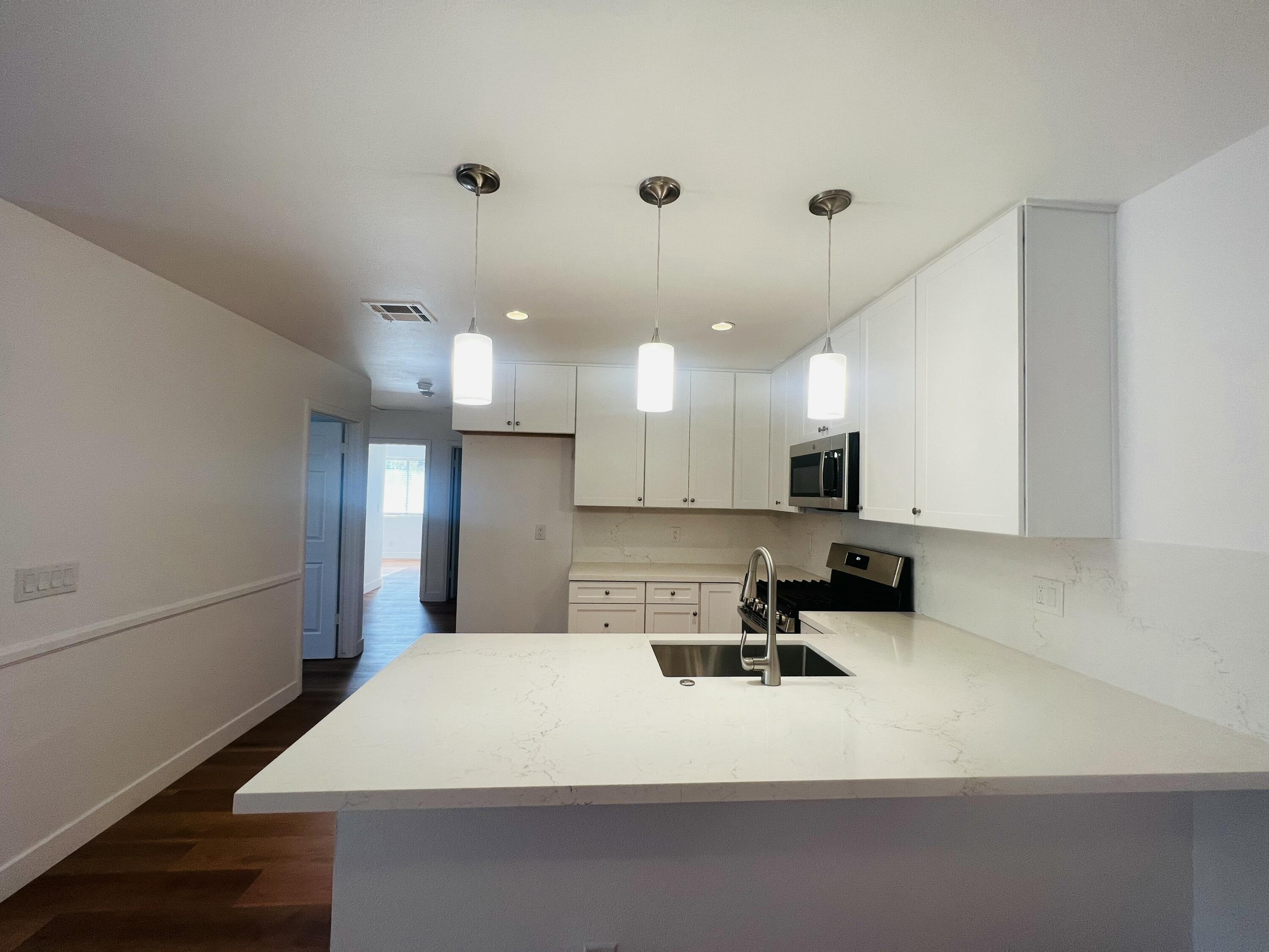 32900 Monte Vista Road Cathedral City, CA 92234 - Photo 7 of 18 a large white kitchen with a refrigerator a sink dishwasher a stove and a refrigerator with wooden floor
