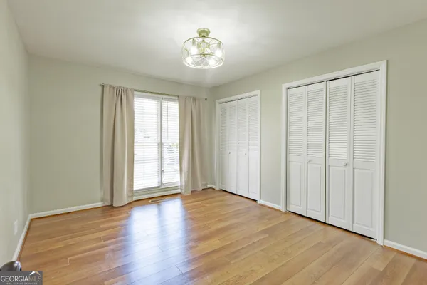 an empty room with wooden floor and windows