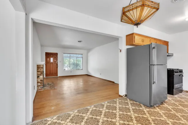 a view of an empty room with window and wooden floor