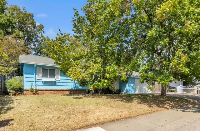 a front view of a house with a yard and trees